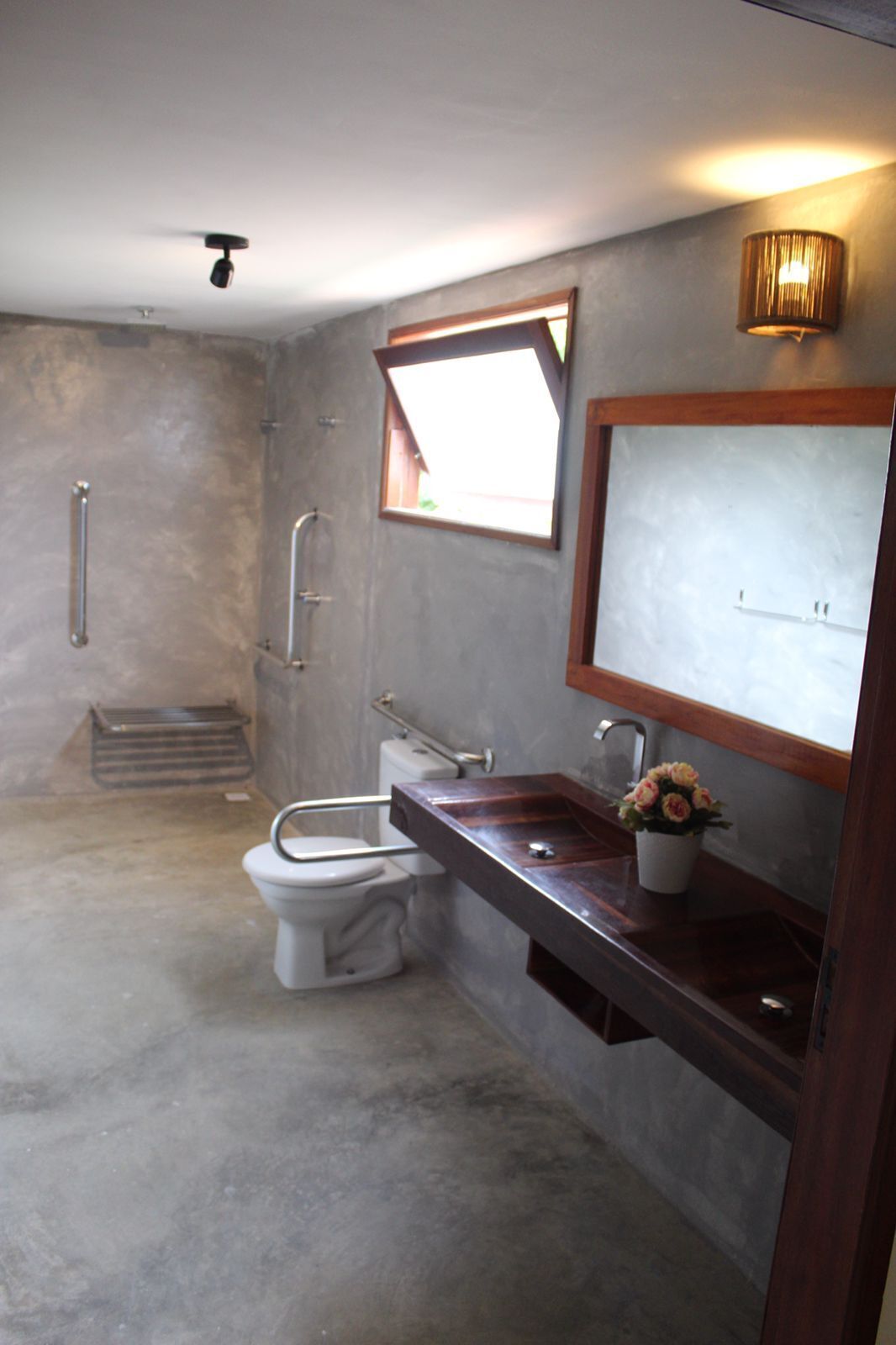 A bathroom with a toilet, a sink, a mirror, and a window.