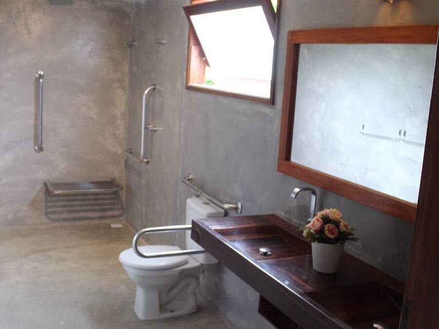 A bathroom with a toilet, a sink, a mirror, and a window.