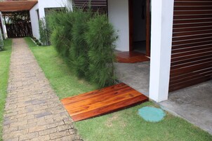 Un sendero conduce a una puerta de madera, rodeado de un césped cuidado y una valla de madera.