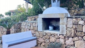 A stone-built outdoor seating area with a stone wall and a covered bench.