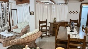 A cozy room with wicker furniture, a dining table, and a vase on the table.