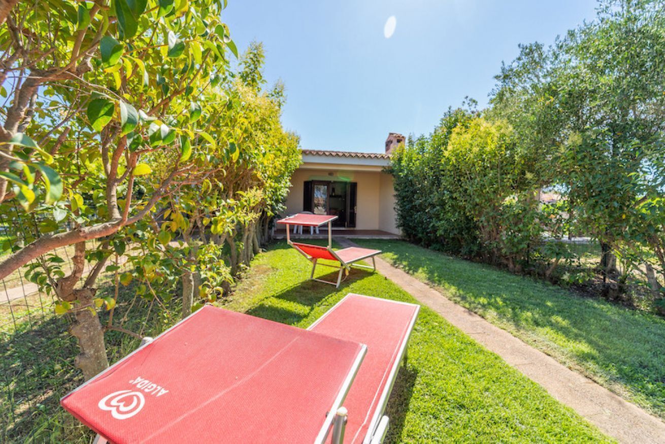 Une cour avec une table de ping-pong, une petite table et un bâtiment en arrière-plan.