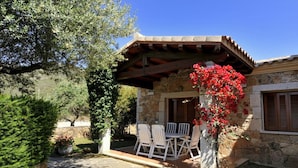 Une maison en pierre dotée d’un patio, d’un espace salon extérieur et d’un jardin.
