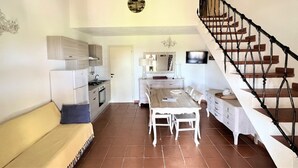 Un amplio salón con mesa de comedor, sofá y escalera.