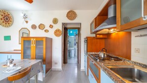Eine moderne Küche mit einer Granitabdeckung, einer Edelstahlspüle und Holzschränken. Ein Esstisch mit Stühlen bietet einen Blick in das angrenzende Badezimmer.