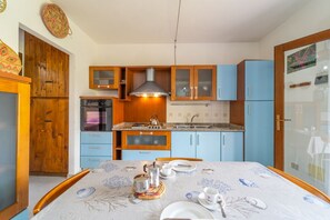 A compact kitchen with wooden cabinets, a built-in oven, and a dining area with a table set for two.