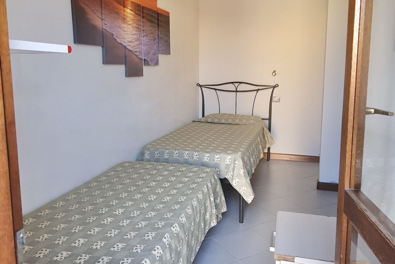 Eine kleine Wohnung mit einem Zimmer, zwei Betten, einer Holztür und einem Fliesenboden.