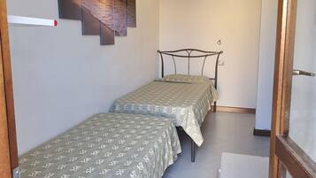 Eine kleine Wohnung mit einem Zimmer, zwei Betten, einer Holztür und einem Fliesenboden.