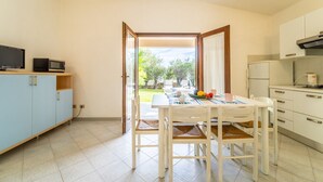 Cozinha compacta com área de refeições, televisão e vista para o exterior.