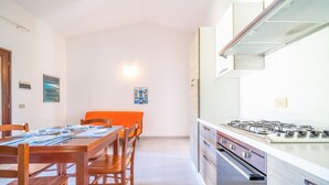 Uma cozinha moderna com fogão a gás, mesa de jantar de madeira e cadeiras.