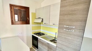 Cocina pequeña con estufa a gas, pileta y muebles de madera.
