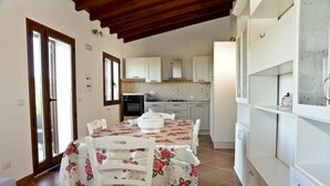 A kitchen with white cabinets, a dining table with chairs, and a tiled floor.