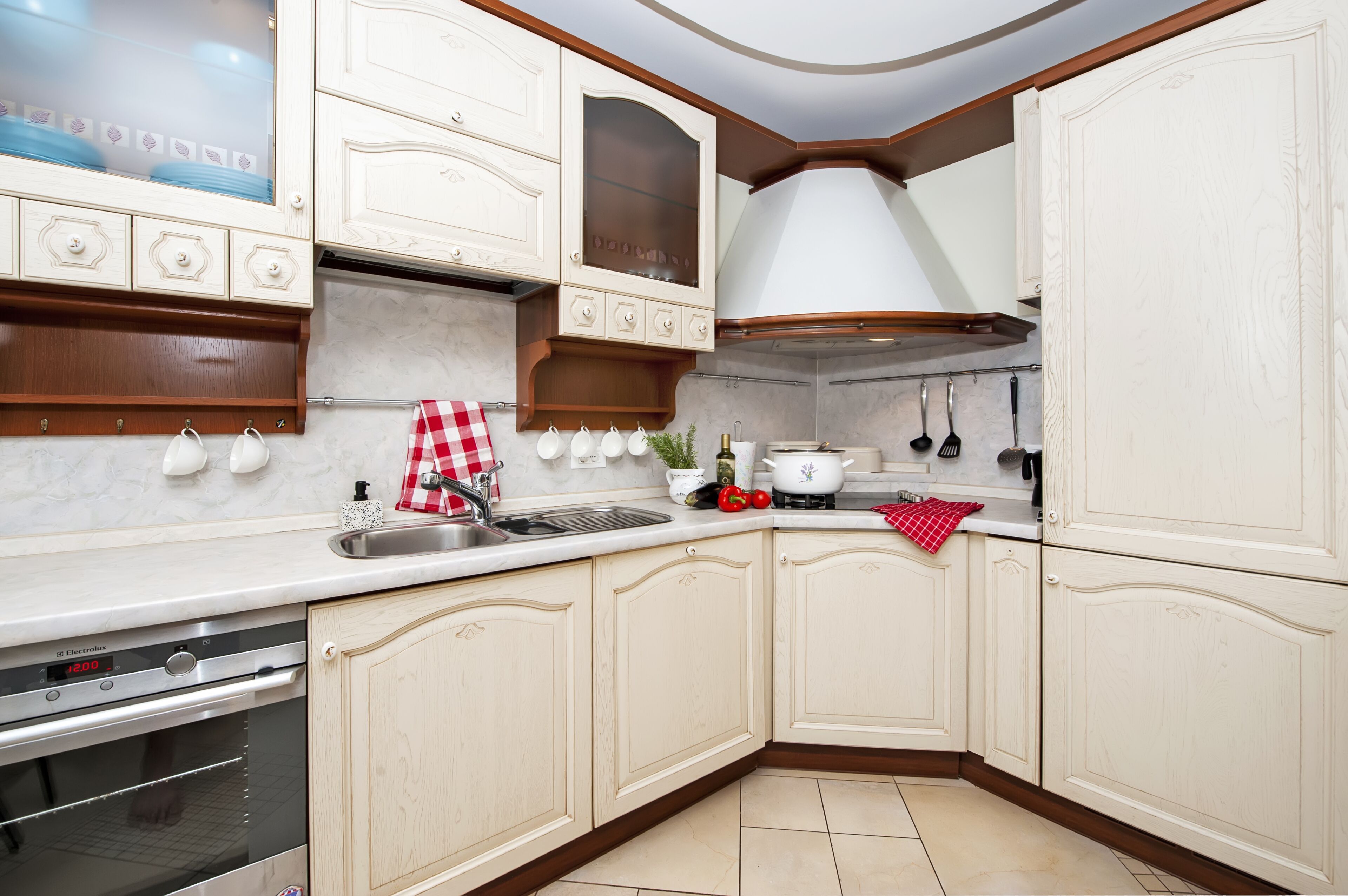 A kitchen with white cabinetry, a built-in oven, and a stainless steel sink.