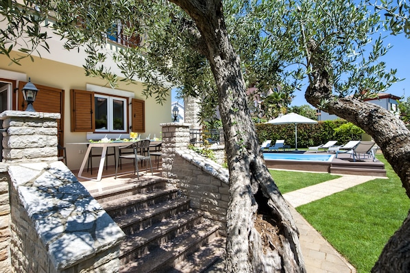 A stone staircase leading to a pool area with outdoor furniture and a dining table.