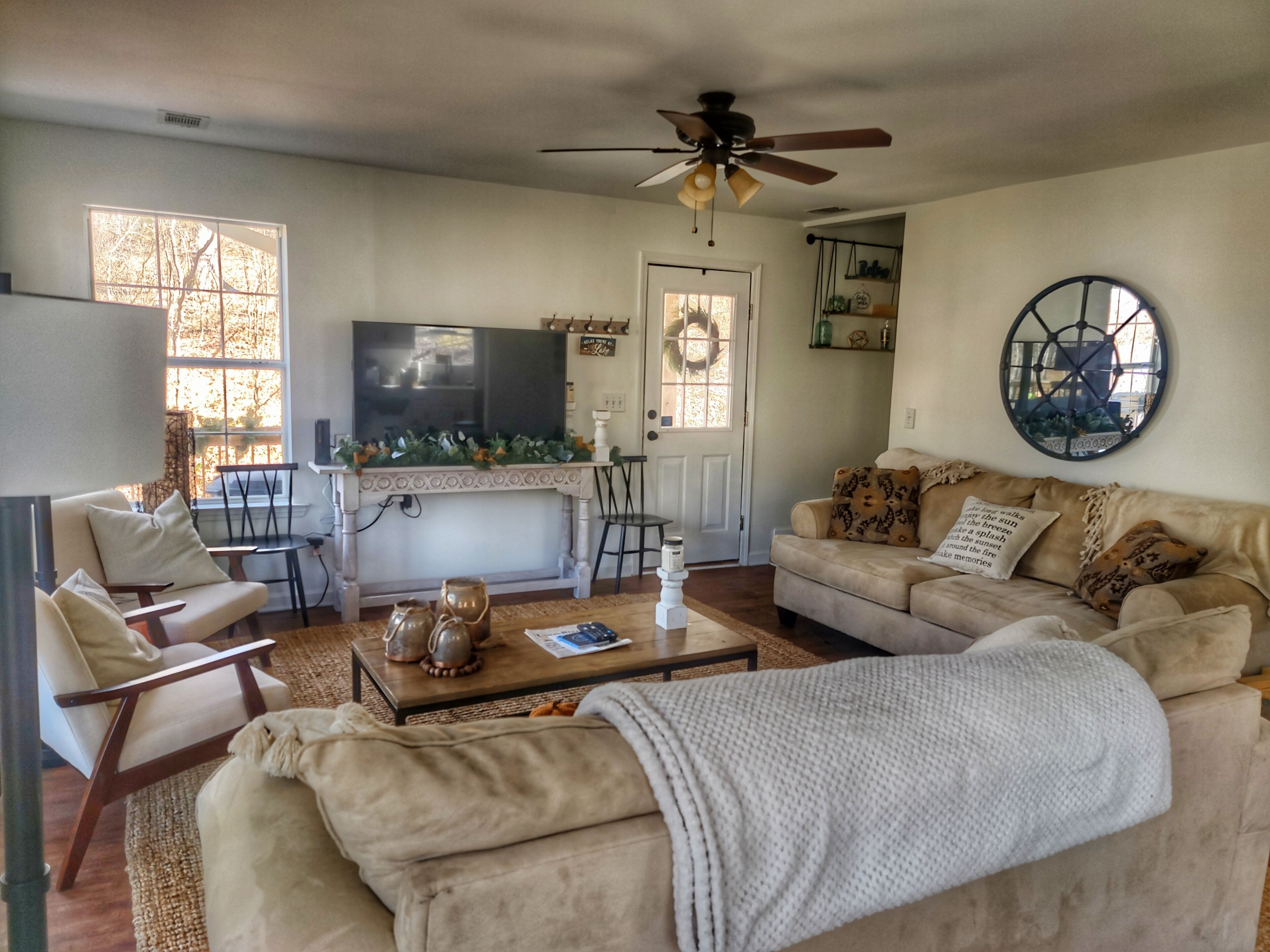 A living room with a sofa, chairs, a coffee table, a television, and a ceiling fan.