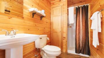 Ein Badezimmer einer Holzhütte mit Waschbecken, Toilette und Dusche.
