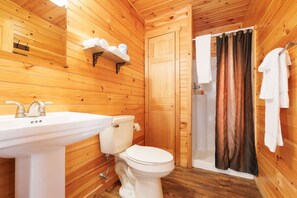 Et badeværelse i en træhytte med vask, toilet og brusebad.