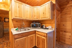 Une cuisine compacte avec des meubles en bois, un évier en acier inoxydable, un four à micro-ondes et une machine à café.