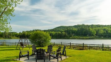 Un espace extérieur aménagé au bord du lac, avec des chaises Adirondack et une balançoire.