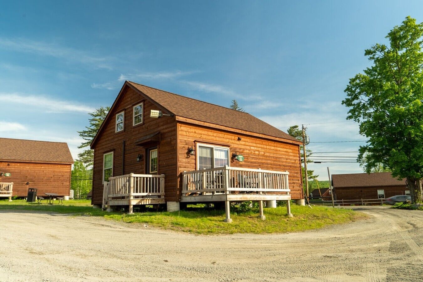 Eine zweistöckige Holzhütte mit Veranda und gepflegtem Schotterweg.