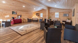 A log cabin interior with a central seating area, a dining table, and artwork on the walls.