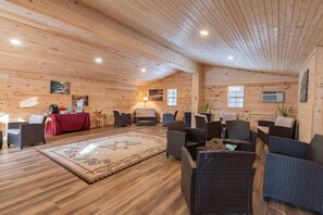 A log cabin interior with a central seating area, a dining table, and artwork on the walls.