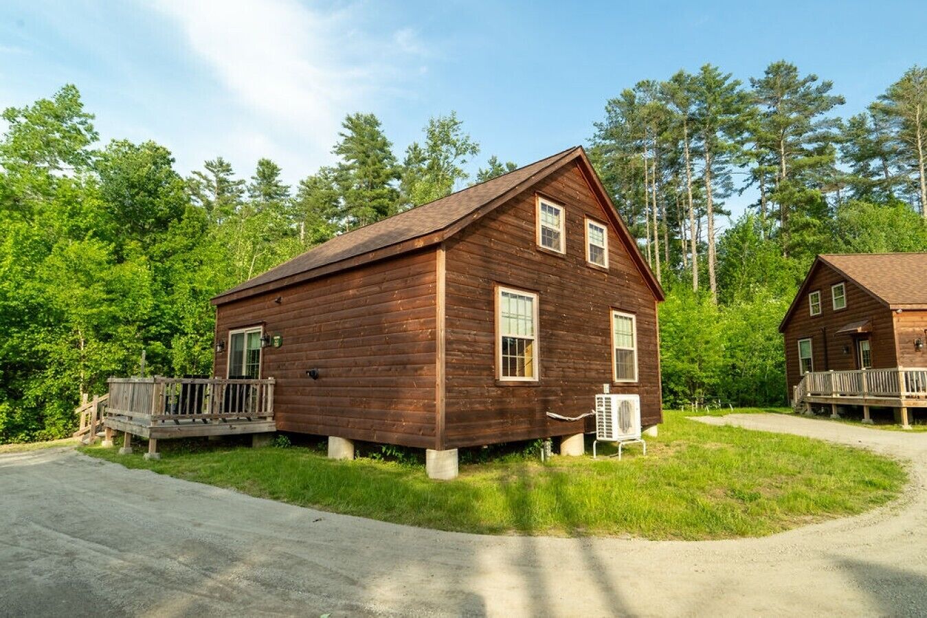 Une cabane en bois dotée d’un porche, d’une petite terrasse et d’un chemin menant à l’entrée.