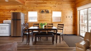 Interior de una cabaña de madera con comedor, cocina y zona de estar.