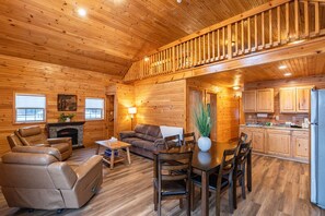 A wooden cabin interior with a living room, dining area, kitchen, and a staircase. - White Mtn Cabin for 14 w/ Lake & Sauna (Bethlehem)