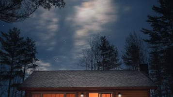 Een chalet met een houten gevel, grote ramen en een veranda.