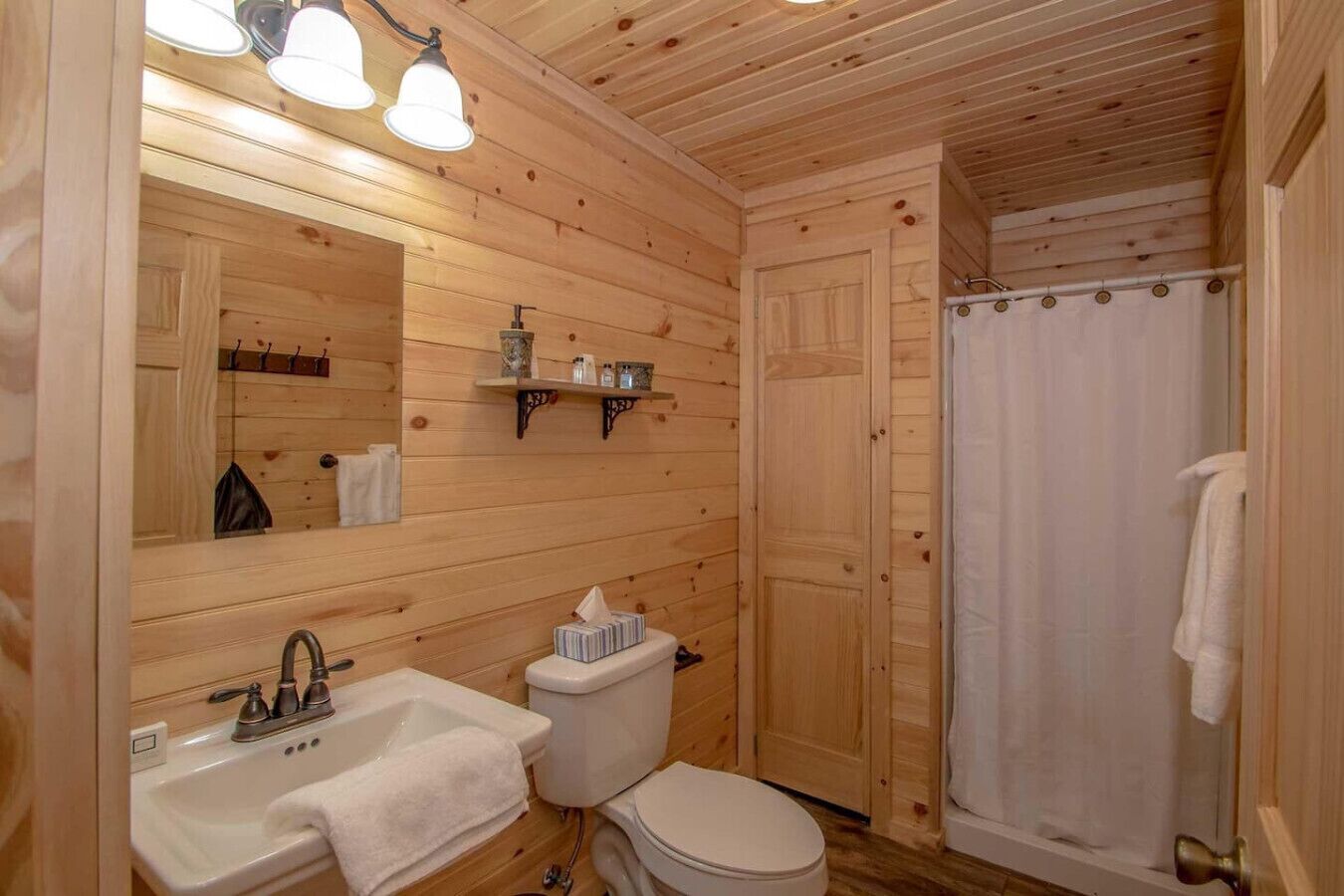 Ein Badezimmer einer Holzhütte mit Waschbecken, Toilette und Dusche.