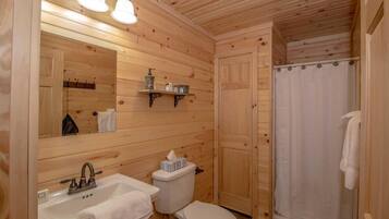 Ein Badezimmer einer Holzhütte mit Waschbecken, Toilette und Dusche.