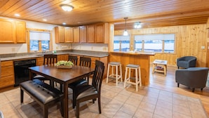 A wooden interior with a kitchen, dining area, bar, and seating.