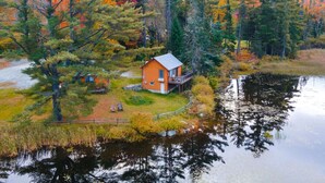 Eine Hütte mit einer Veranda, umgeben von einem Teich und dichtem Wald.