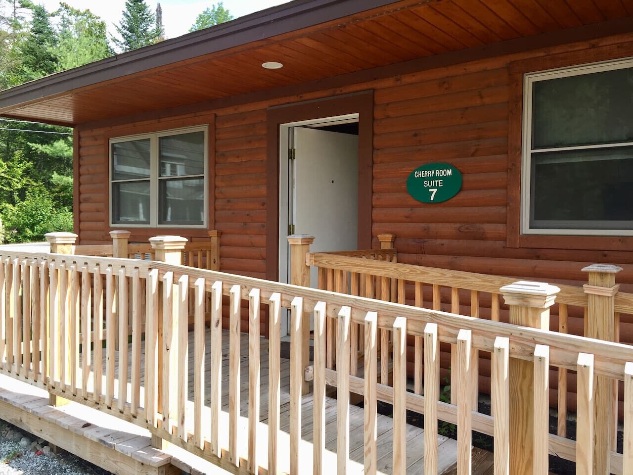 A wooden cabin with a porch and a sign indicating "CHERRY ROOM SUITE 7".