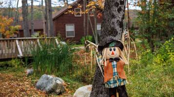 A rustic cabin with a wooden exterior and a window, surrounded by a natural landscape with trees and a wooden deck.