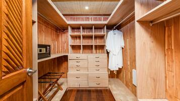 A wooden closet with multiple drawers and shelves, a hanging rack, and a small shelf with a clock.