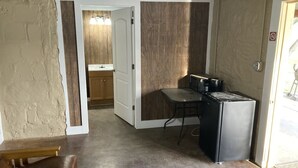 A compact kitchen with a refrigerator, a sink, and a dining area with a bench.