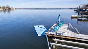 A dock with a boat, a row of chairs, and a blue umbrella. - Hottub/Firepit/Lakefront/Outdoor TV/Bunkbeds (Granite Shoals)