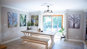 A spacious room with a wooden bench, a dining table, and a view through a large window. - A-Frame Arbor One Block From The Beach-Four Beds and Four Bathrooms! (Madison)