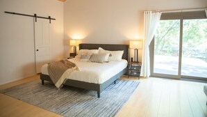 A bedroom with a bed, bedside lamps, a sliding door, and a view of the outdoors. - A-Frame Arbor One Block From The Beach-Four Beds and Four Bathrooms! (Madison)