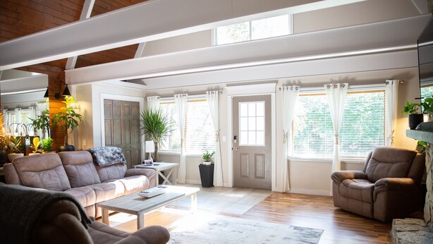 A spacious living room with a high ceiling, wooden beams, a leather sofa, a coffee table, and a potted plant. - A-Frame Arbor One Block From The Beach-Four Beds and Four Bathrooms! (Madison)