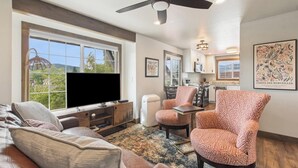 Ein Wohnzimmer mit Sofa, Sesseln, Fernseher und Deckenventilator.
