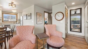 Ein modernes Wohnzimmer mit gemusterten Möbeln, einem Essbereich und Blick durch ein großes Fenster.