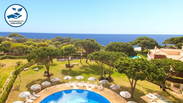 A pool area with lounge chairs and umbrellas, surrounded by trees and a view of the sea. - Modern Apartment with Pool – Albufeira (Albufeira)