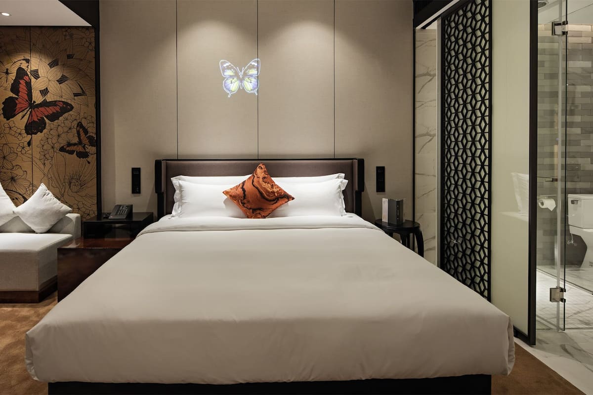 Una habitación de hotel moderna con una cama grande, una mesita de noche y un cuadro decorativo de mariposas en la pared.