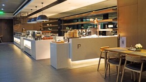 Ein modernes Restaurant mit Bar im Zentrum, Holztischen und Pendelleuchten.