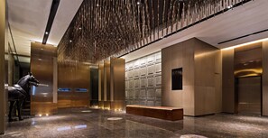 A modern interior with a metallic horse sculpture, a bench, and a wall with a unique pattern. - Paco Hotel Chebeinan Metro Guanghzou (Guangzhou)