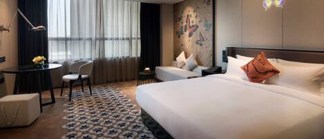 A hotel room with a large bed, a desk, a chair, and a small table.