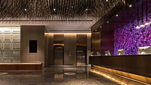 Eine moderne Lobby mit einer Rezeption, Aufzügen und einer Wand mit kreisförmigen Mustern.